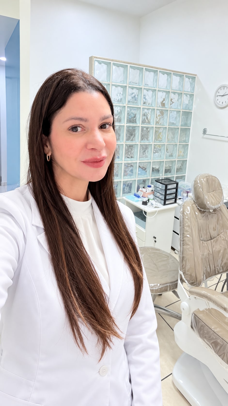 Dra. Ana Cecília Grimaldi com jaleco branco em seu consultório odontológico
